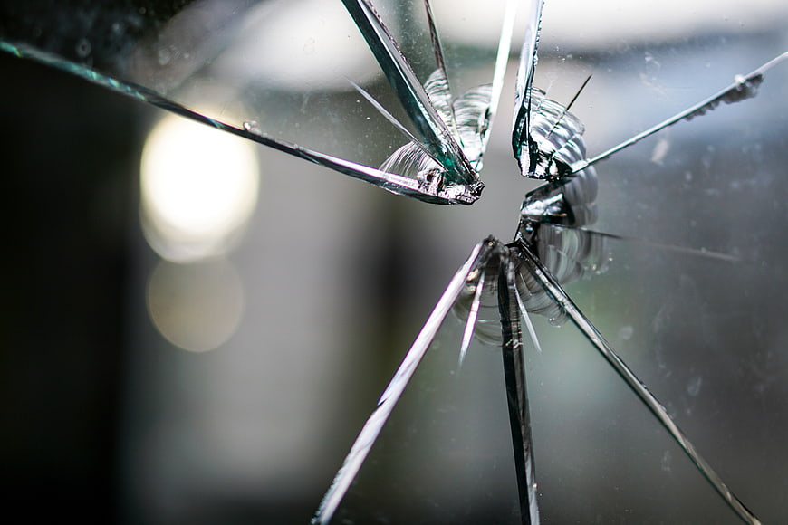 Close-up of shattered glass with bullet hole impact point