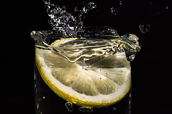 Refreshing lemon slice splashing into clear water glass