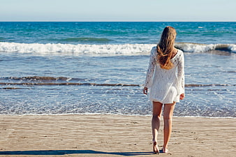 Woman in White Lace Dress Walking on Sandy Beach