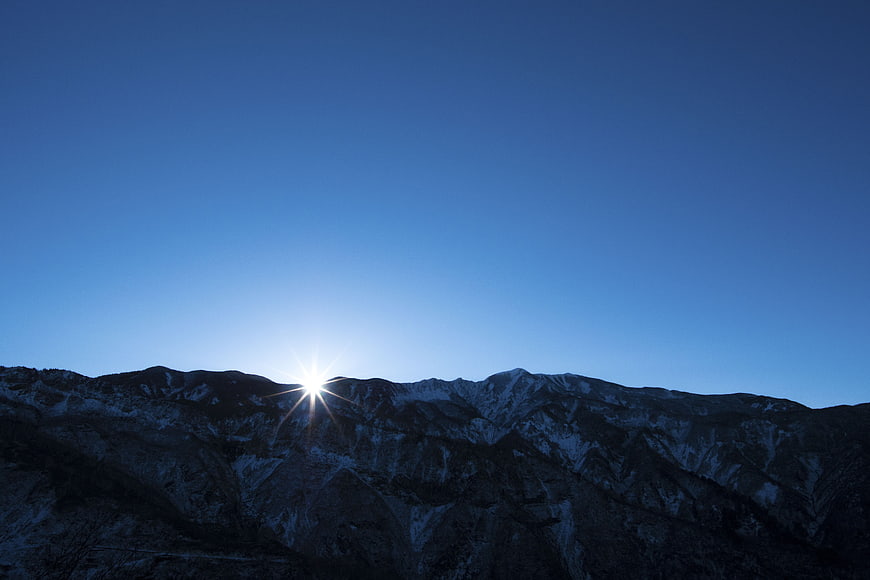 Sunburst over Snow-Capped Mountain Range at Dusk