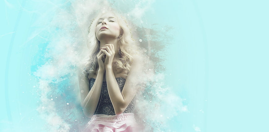 Dreamy blonde woman praying with ethereal blue background
