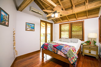 Cozy beach house bedroom with wooden ceiling and colorful quilt