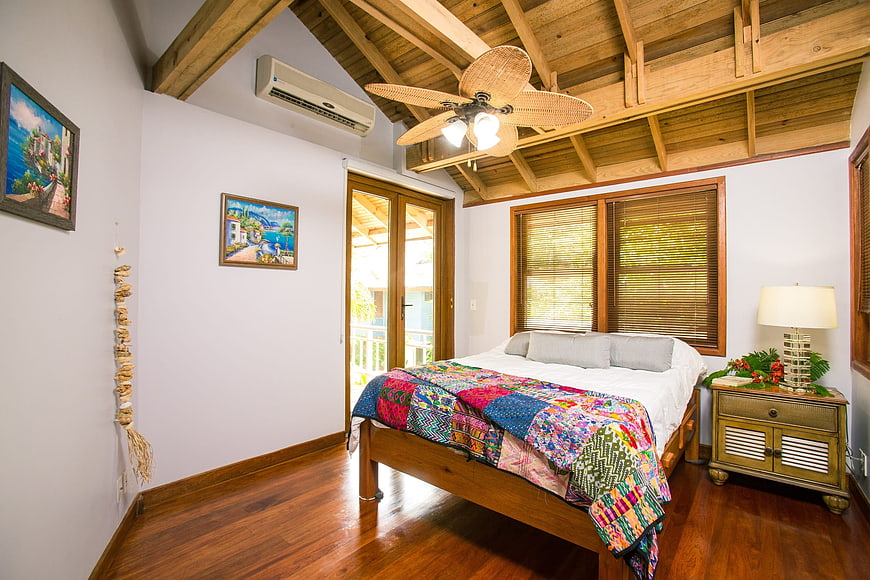 Cozy beach house bedroom with wooden ceiling and colorful quilt