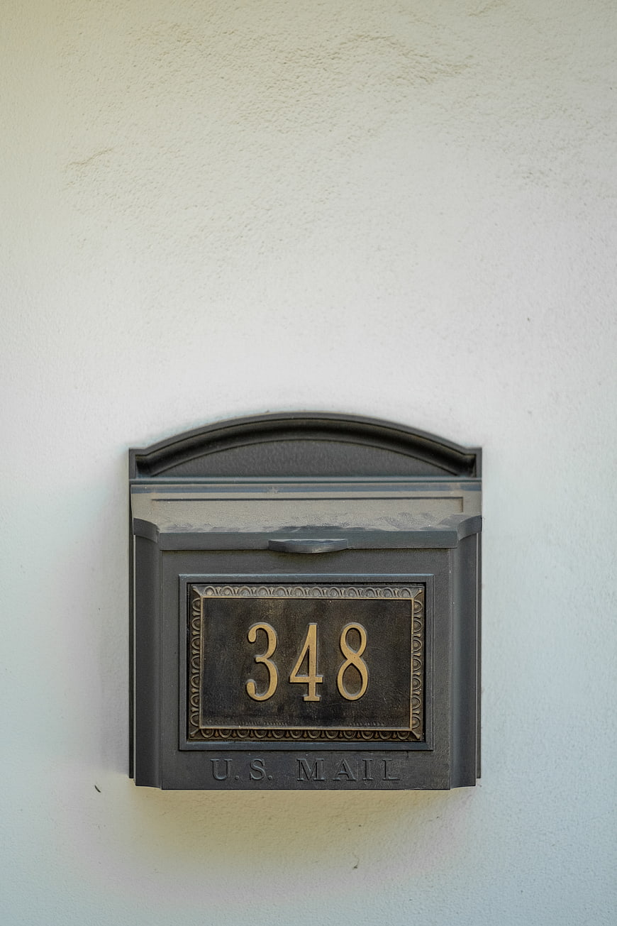 Black Wall Mailbox with House Number 348 on White Stucco