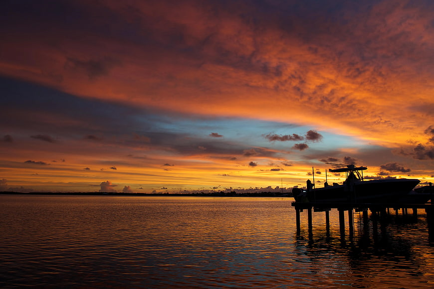 Dramatic Sunset Sky Over Water with Silhouetted Boat Dock
