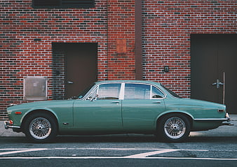 Vintage Green Classic Car Parked Against Red Brick Wall