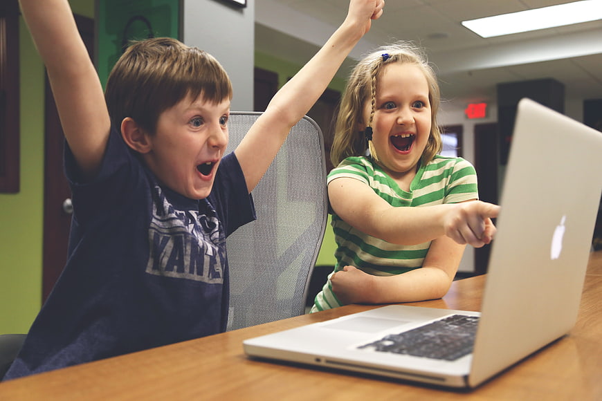 Excited children celebrating success on a laptop computer