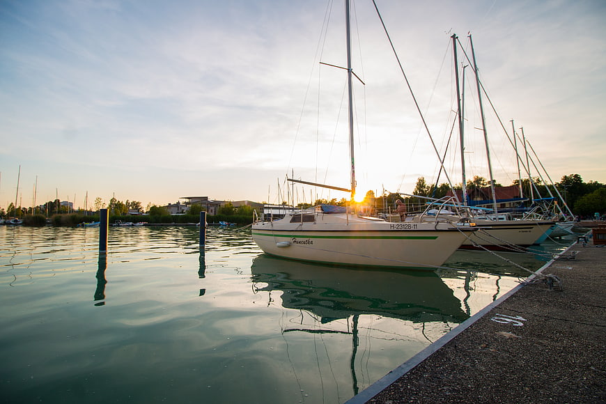 Sailboats docked at sunset in a calm marina