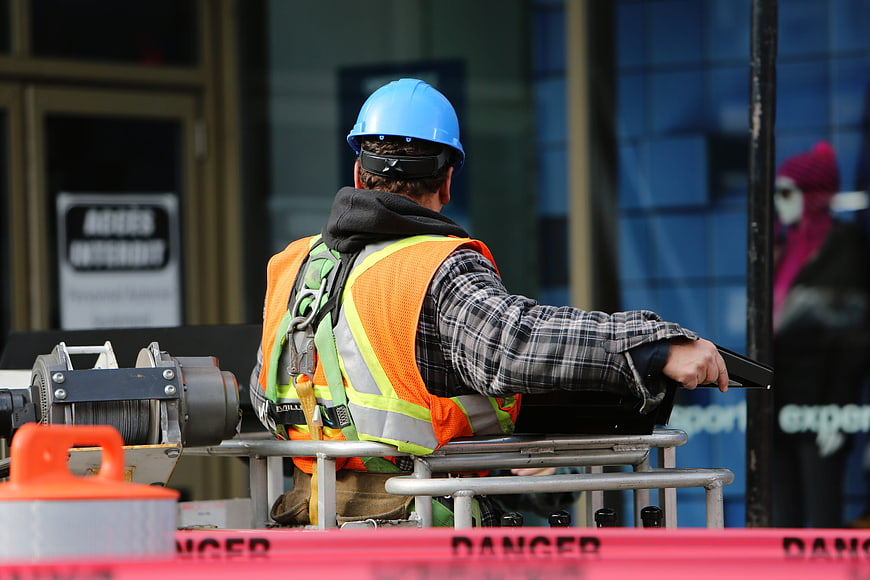 Construction worker on lift with safety gear and danger tape