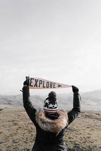 Woman holding explore pennant in winter landscape