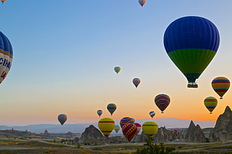 Hot Air Balloons Flying Over Cappadocia Landscape at Sunset