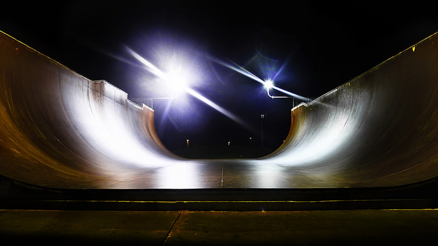 Empty concrete halfpipe illuminated by bright lights at night