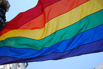 Rainbow Pride Flag Waving Against Blue Sky