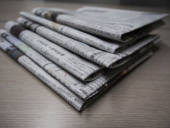 Stack of folded Japanese newspapers on a wooden table
