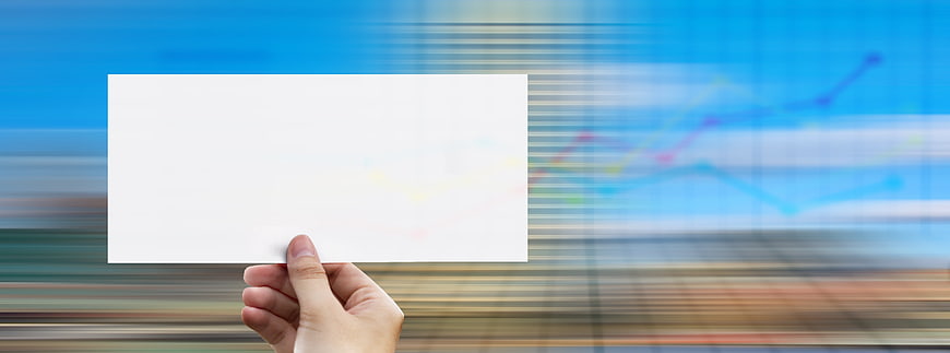 Hand holding blank white card against blurred business chart background
