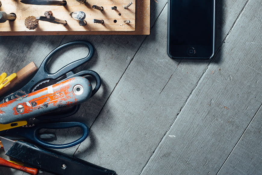 Top view of vintage tools and smartphone on gray wooden table
