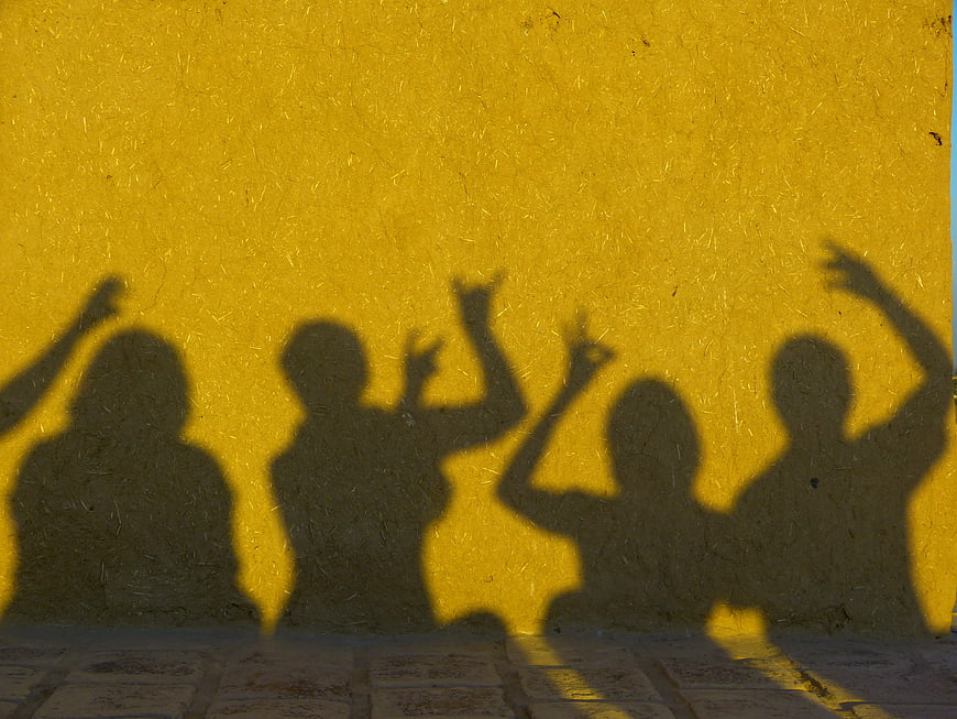 Silhouettes of people dancing on a yellow wall