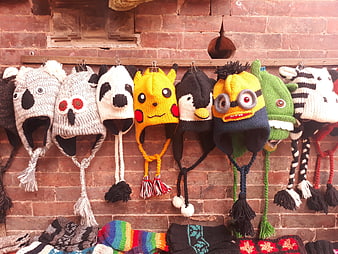 Colorful Knitted Animal Hats Hanging on Brick Wall