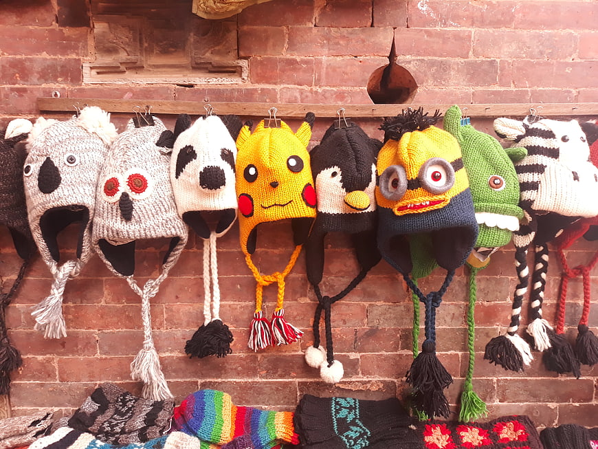 Colorful Knitted Animal Hats Hanging on Brick Wall