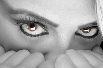 Close-up of woman's eyes with selective color and hands covering mouth