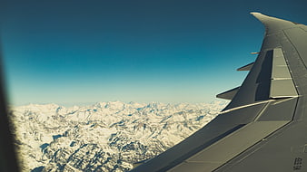 Airplane Wing View Over Snowy Mountain Range