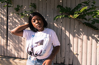 Young Black Woman in Graphic Tee Against Wooden Fence