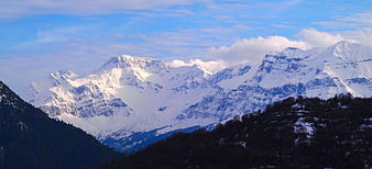Panoramic view of snow-capped mountain peaks with blue sky