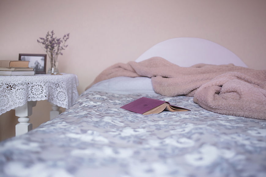 Cozy Bedroom Interior with Open Book and Pink Blanket