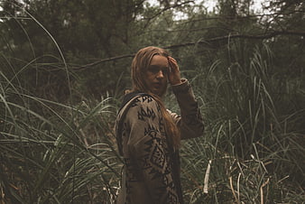 Woman in Patterned Hoodie Standing in Tall Forest Grass