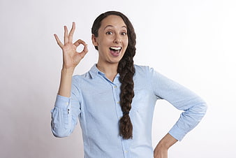 Excited woman making OK hand gesture on white background