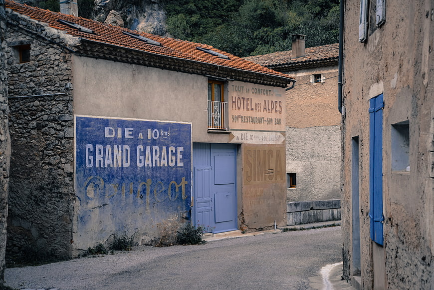 Vintage French Village Street with Faded Hotel and Garage Signs