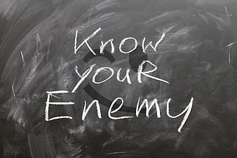 Know Your Enemy Chalk Text on Smudged Blackboard Background