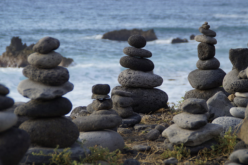Stacked Stone Cairns on Rocky Coastline with Ocean Background