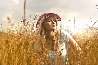 Serene Woman in Straw Hat Relaxing in Golden Wheat Field