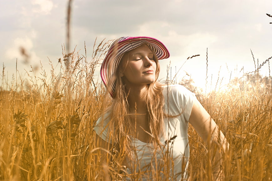 Serene Woman in Straw Hat Relaxing in Golden Wheat Field