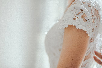 Close-up of bride's arm in white lace wedding dress