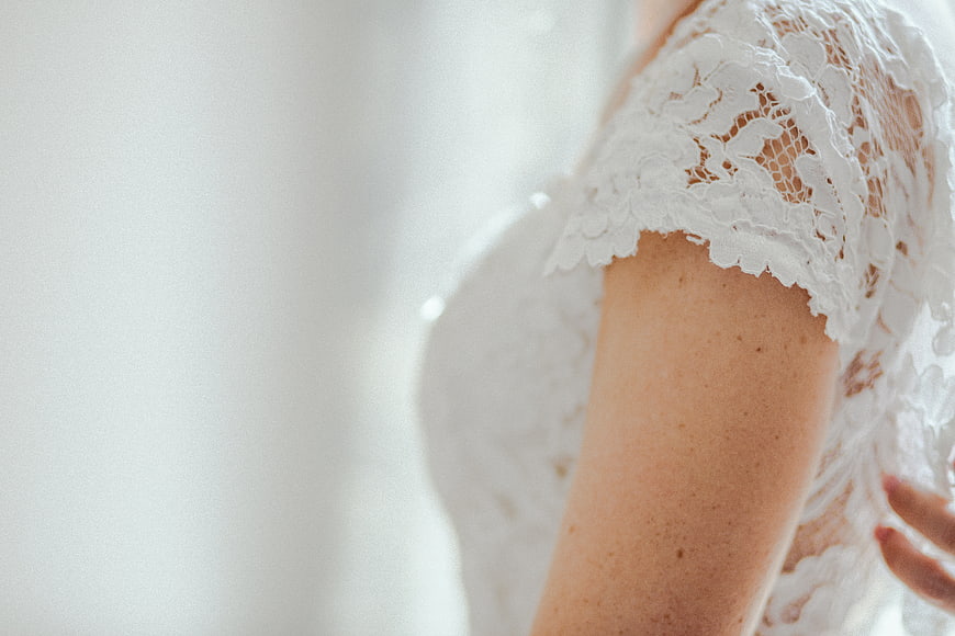 Close-up of bride's arm in white lace wedding dress
