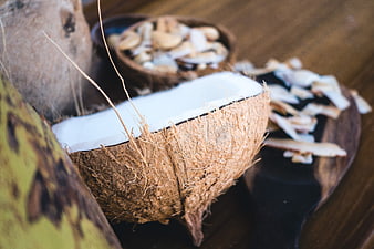 Fresh coconut cut in half with dried chips on wooden board