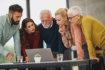 Multi-generational team collaborating on laptop in modern office