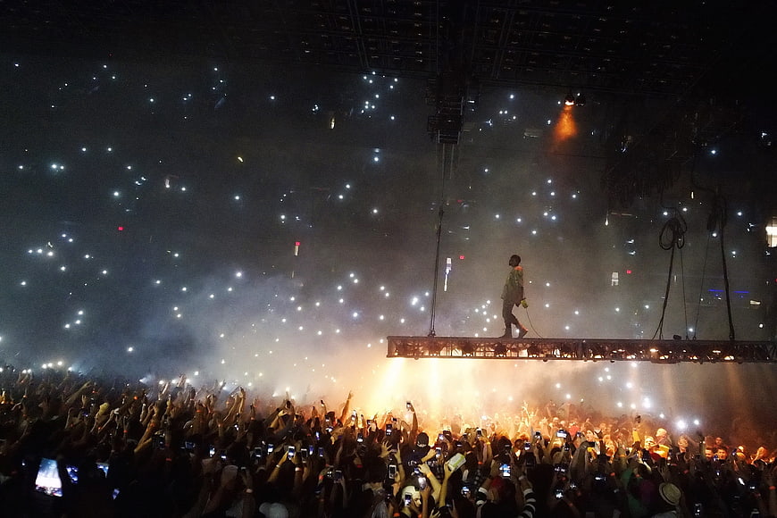 Singer performing on stage with crowd holding up lights