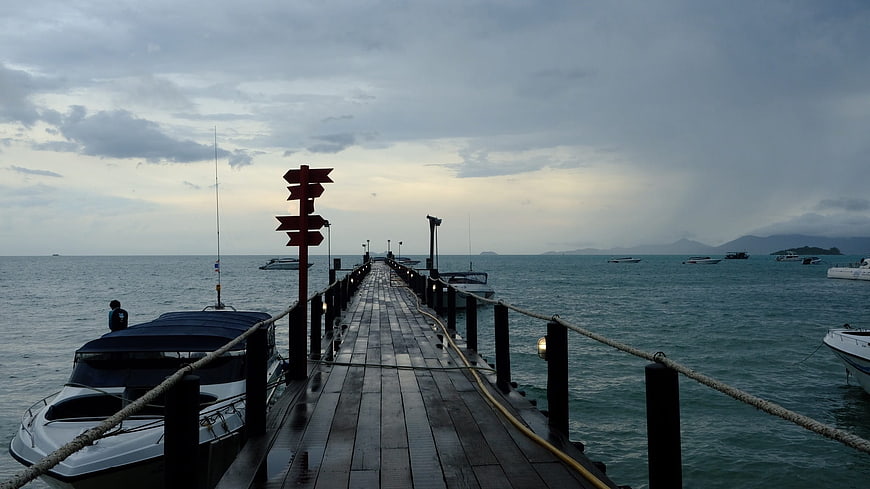 Wet wooden pier extending into calm sea at dusk