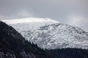 Snow-Capped Mountain Peak with Dark Forest Slopes