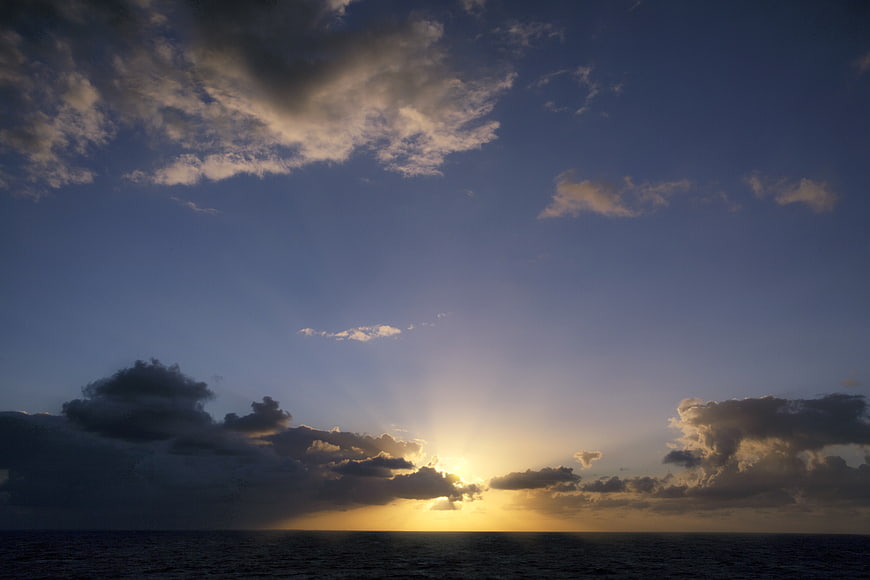 Dramatic sunset over ocean with sun rays through clouds