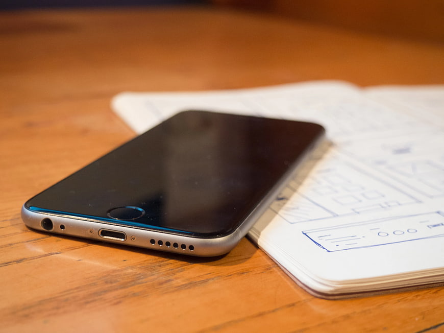 Smartphone on Sketchbook with Wireframe Designs
