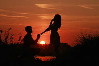 Silhouette of couple making a marriage proposal at sunset