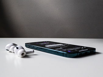 Smartphone and Wireless Earbuds on White Surface