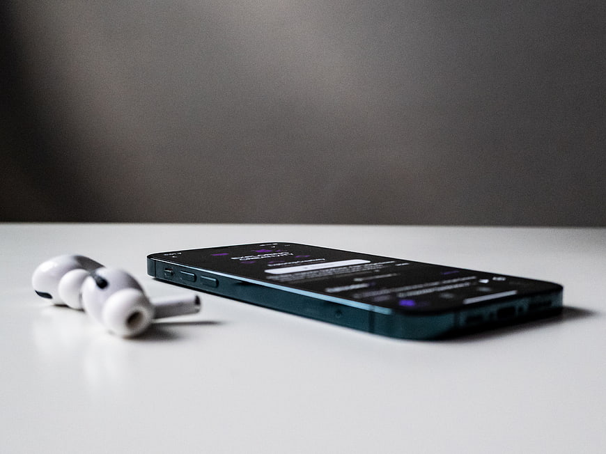 Smartphone and Wireless Earbuds on White Surface