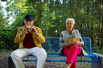Senior couple sitting on a blue park bench in a forest