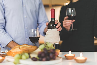 Couple Holding Wine Bottle with Cheese and Grapes