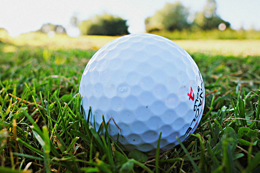 Close-up of white golf ball resting on green grass